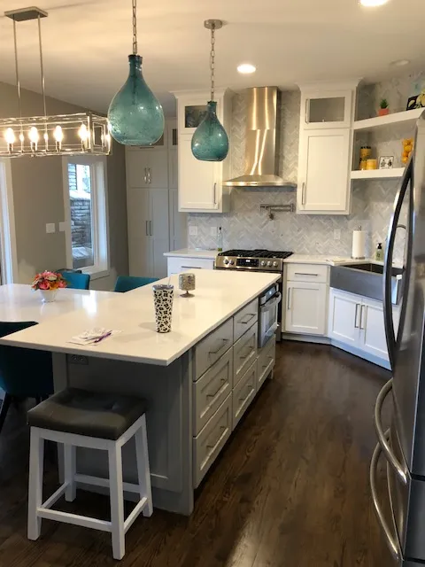 Remodeled kitchen with a white quartz island, grey island cabinets and blue glass pendant lights
